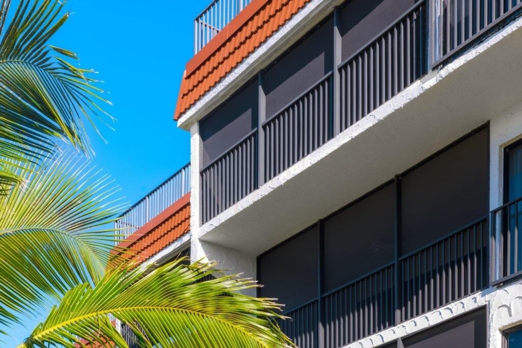 A multi-story building with balconies, large windows, and a clear blue sky.