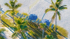 An aerial view of a beach with palm trees, sun loungers, and umbrellas. - Pointe Santo E44 3 Bedroom Condo (Sanibel)