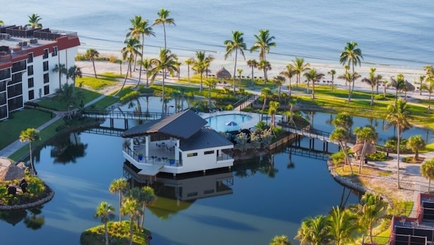 A resort with a pool, palm trees, and a beach view. - Pointe Santo D35 2 Bedroom Condo (Sanibel)
