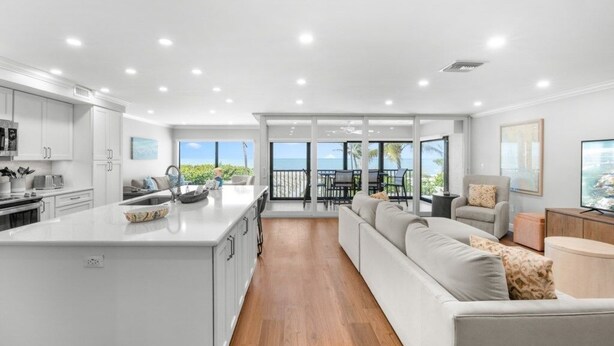 Una cocina moderna con armarios blancos, una isla central y un comedor con vistas.
