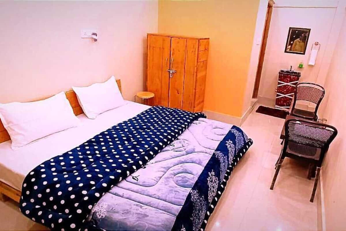 A bedroom with a bed, a wardrobe, a chair, and a small table.