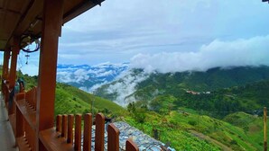 A wooden balcony overlooking a mountainous landscape with lush greenery and a view of the valley below. - VEDA INN (Kalsi)