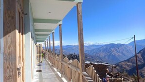 A corridor with wooden posts and a view of snow-capped mountains. - VEDA INN (Kalsi)