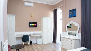 Een slaapkamer met een bed, een bureau, een stoel, een kledingkast, een dressoir, een televisie en een spiegel.