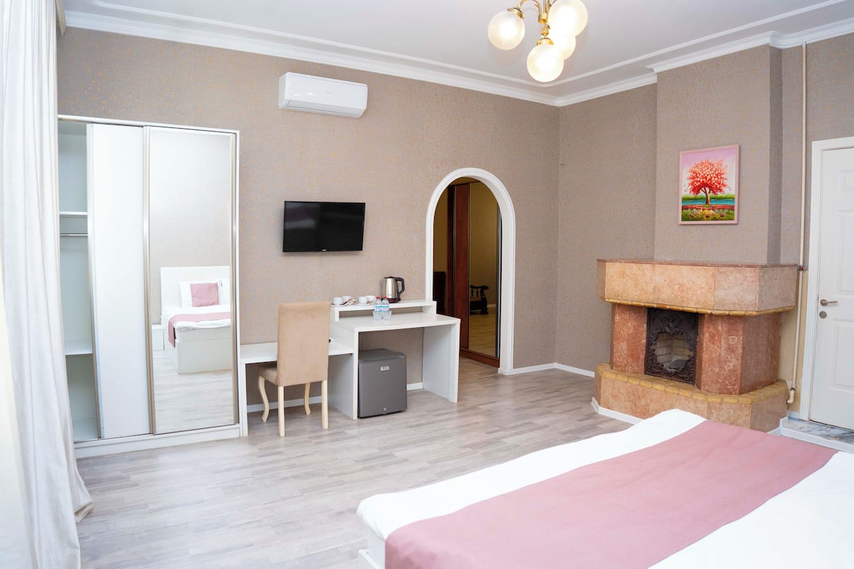 Une chambre d’hôtel équipée d’un lit, d’un bureau, d’une chaise, d’une télévision, d’une cheminée et d’une armoire.