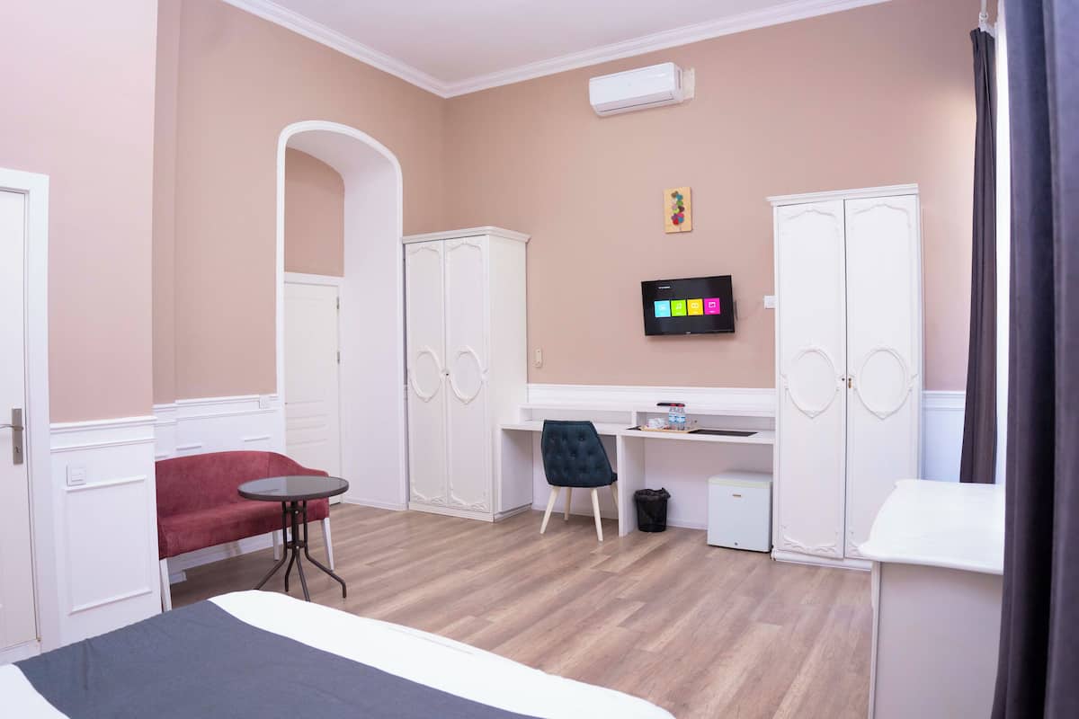 Une chambre avec un lit, un bureau, une chaise, une armoire et un téléviseur.