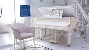 Een vleugelpiano in een goed verlichte kamer met een marmeren vloer en een trap op de achtergrond.