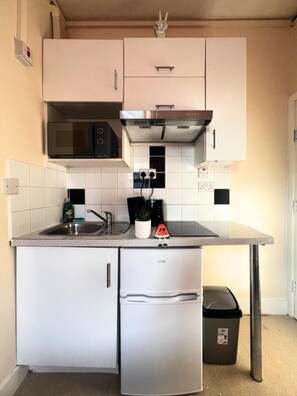 Una cocina compacta con microondas, estufa, fregadero y un refrigerador pequeño.