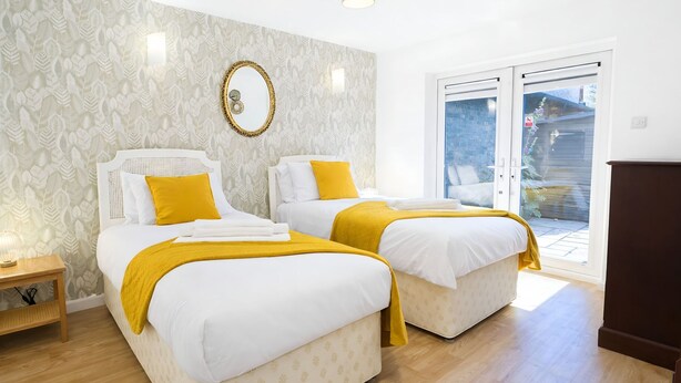 Ein Hotelzimmer mit zwei Betten, einem großen Spiegel und einer Schiebeglastür nach draußen.