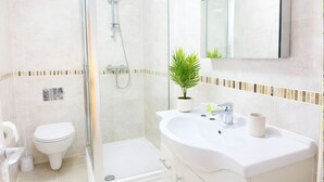 Ein modernes Badezimmer mit einer Duschkabine aus Glas, einer weißen Toilette und einem Waschbecken mit Spiegel darüber.