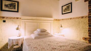 Une chambre à coucher avec un lit, deux tables de chevet, une lampe et des tableaux encadrés accrochés aux murs.
