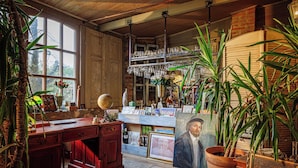 A rustic room with a wooden desk, shelves with glassware, and a large window. - Vila Terrasse (Kosice)