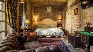 A cozy bedroom with a large bed, a leather sofa, a billiards table, and a brick wall. - Vila Terrasse (Kosice)