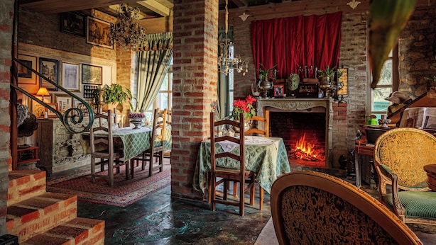 A cozy room with a fireplace, wooden furniture, and a staircase leading to another area. - Vila Terrasse (Kosice)