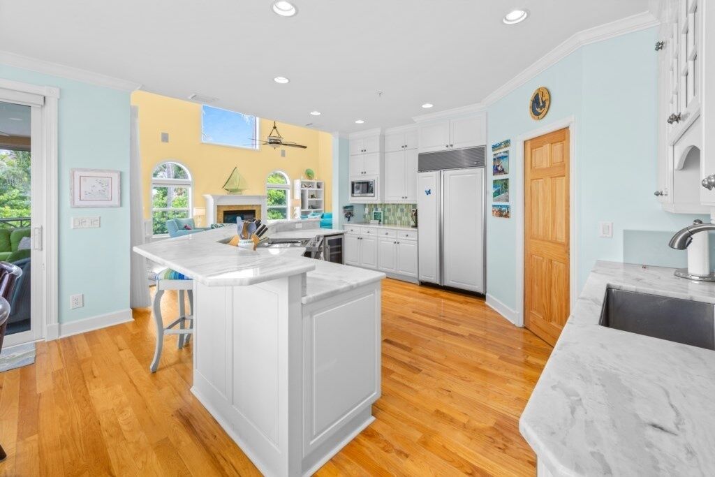 Une cuisine moderne avec des meubles blancs, un îlot central et un plancher en bois.