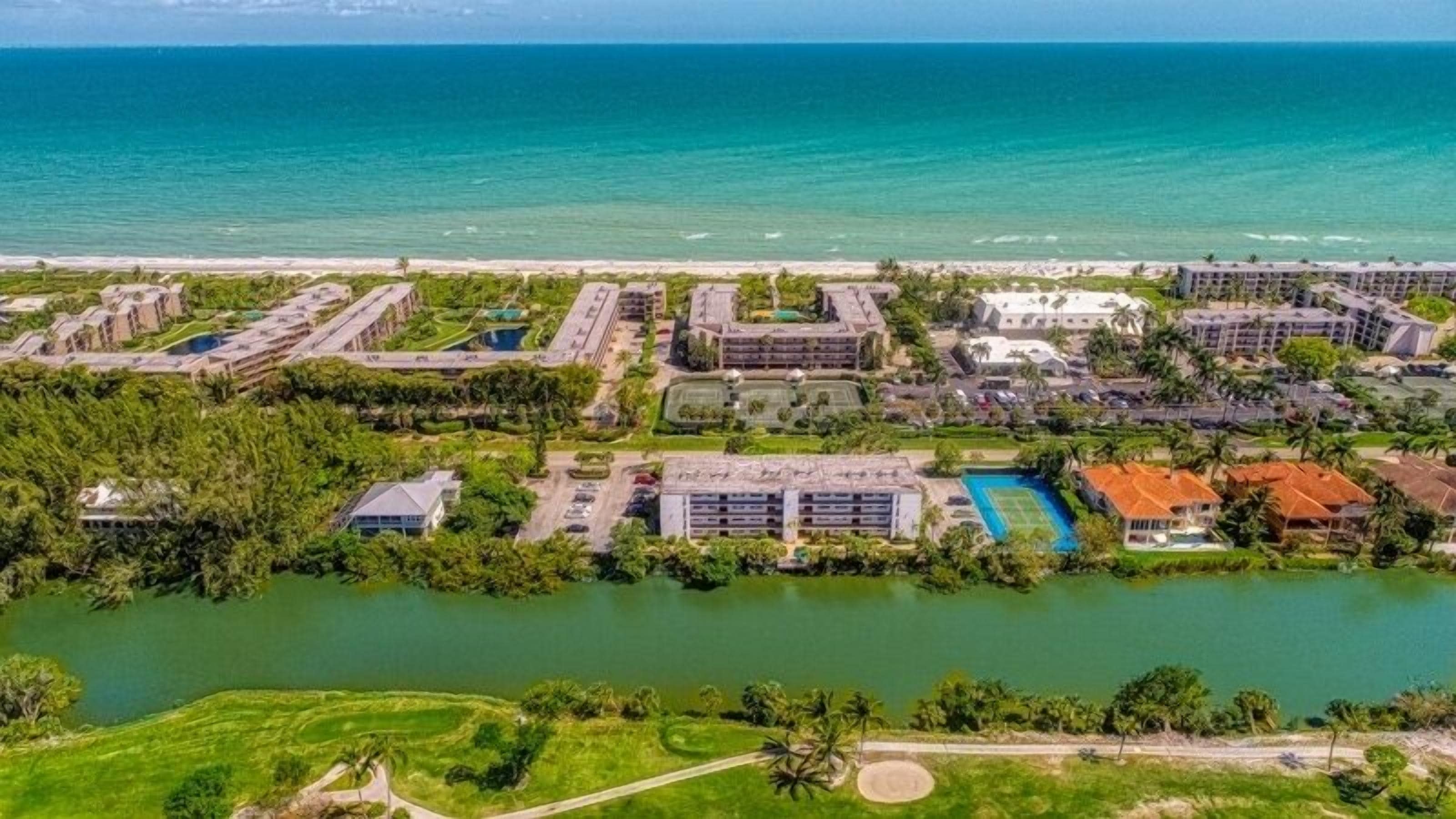 Luftaufnahme eines Resorts mit mehreren Gebäuden, einem Swimmingpool und direktem Strandzugang.