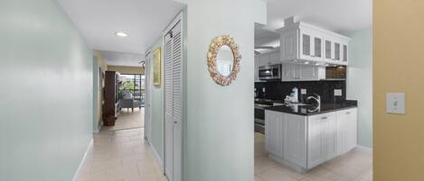 Una cocina moderna con armarios blancos, encimera negra y un adorno decorativo en la pared.
