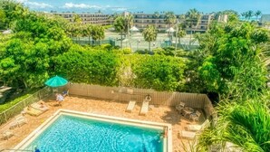 A rooftop pool area with a view of surrounding buildings and palm trees. - Sandpebble 3f 2 Bedroom Condo (Sanibel)