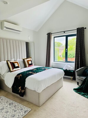 Ein modernes Schlafzimmer mit einem großen Bett, einer Bank, einem Sessel und einem Fenster mit Vorhängen.