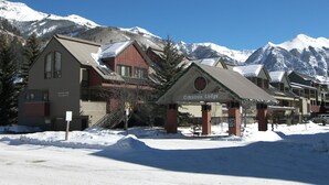 A lodge with a snow-covered entrance and mountains in the background. - Alpine Escape 1 Bedroom Condo (Telluride)