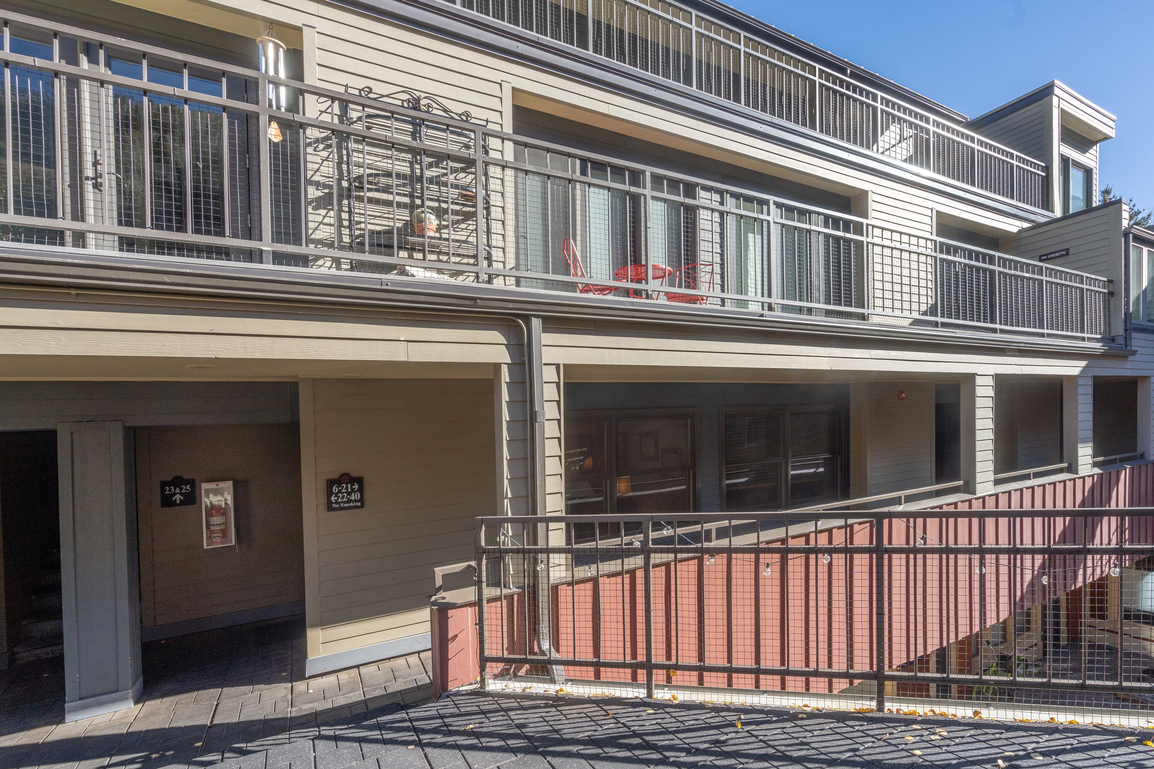 Un hôtel à plusieurs étages doté d’un balcon à l’étage supérieur, d’un panneau indiquant l’emplacement d’un extincteur et d’un escalier menant à l’entrée.