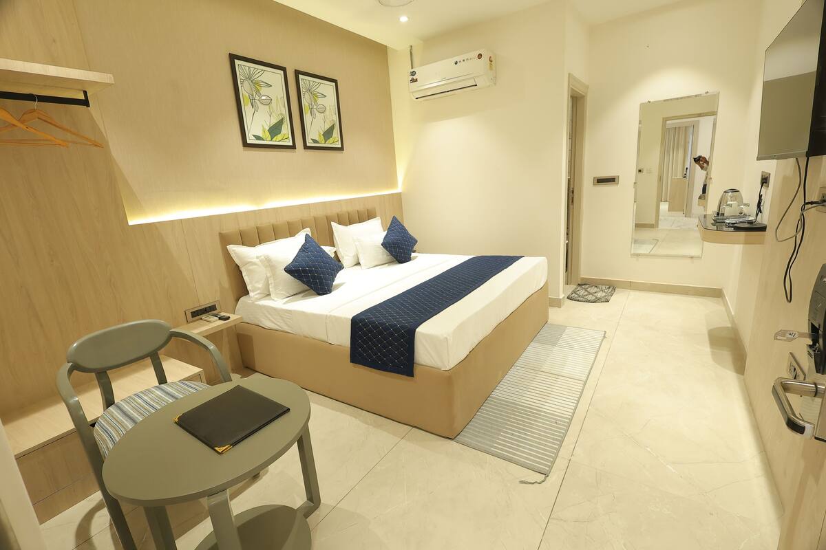 Une chambre d’hôtel moderne équipée d’un lit, d’un bureau, d’une chaise, d’une télévision et d’un appareil de climatisation.