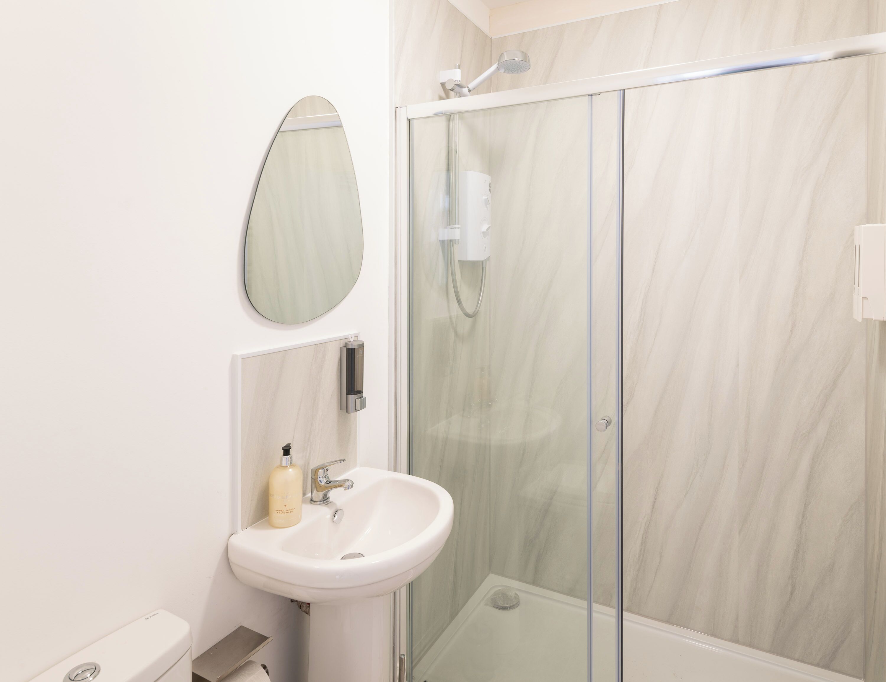 A modern bathroom with a glass-enclosed shower, a white sink, and a mirror.