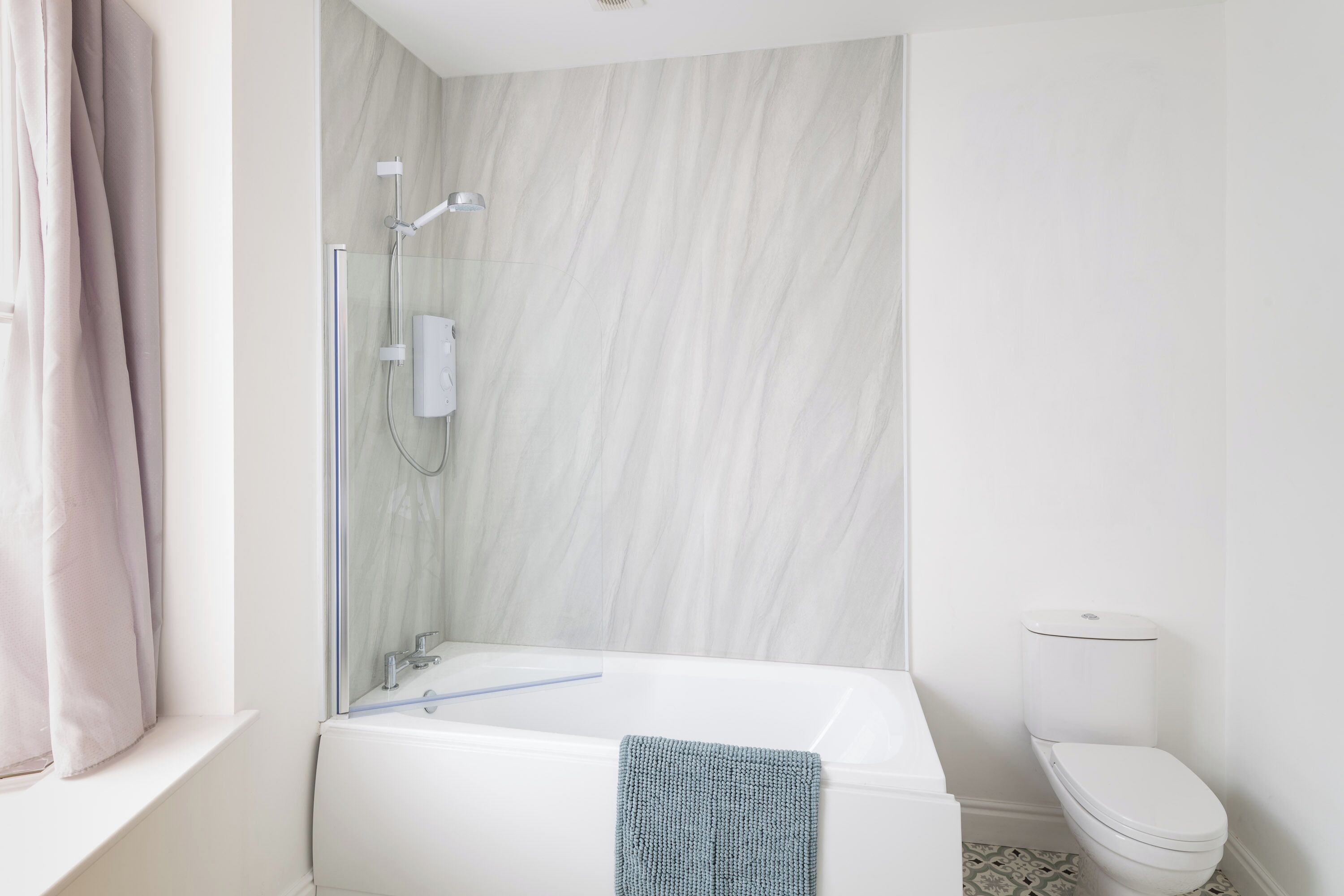 A modern bathroom with a glass-enclosed shower, a white bathtub, and a toilet.