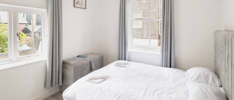 A bedroom with a bed, a window, and a small table.