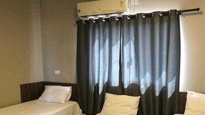 A hotel room with two single beds, a table with a towel, and a window with curtains. - HOTEL NOVA AMERICA (Tres Lagoas)