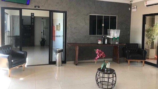 A modern lobby with a flat-screen TV, a reception desk, a coffee machine, and two sofas. - HOTEL NOVA AMERICA (Tres Lagoas)