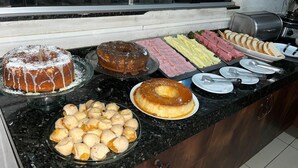 A buffet with various food items including a bundt cake, a chocolate cake, and several types of meat and cheese. - HOTEL NOVA AMERICA (Tres Lagoas)