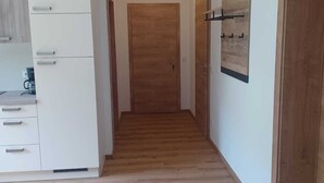 Un pasillo con piso de madera, armarios blancos y una puerta de madera al final.