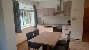 Una cocina compacta con mesa y sillas, horno empotrado y cafetera.