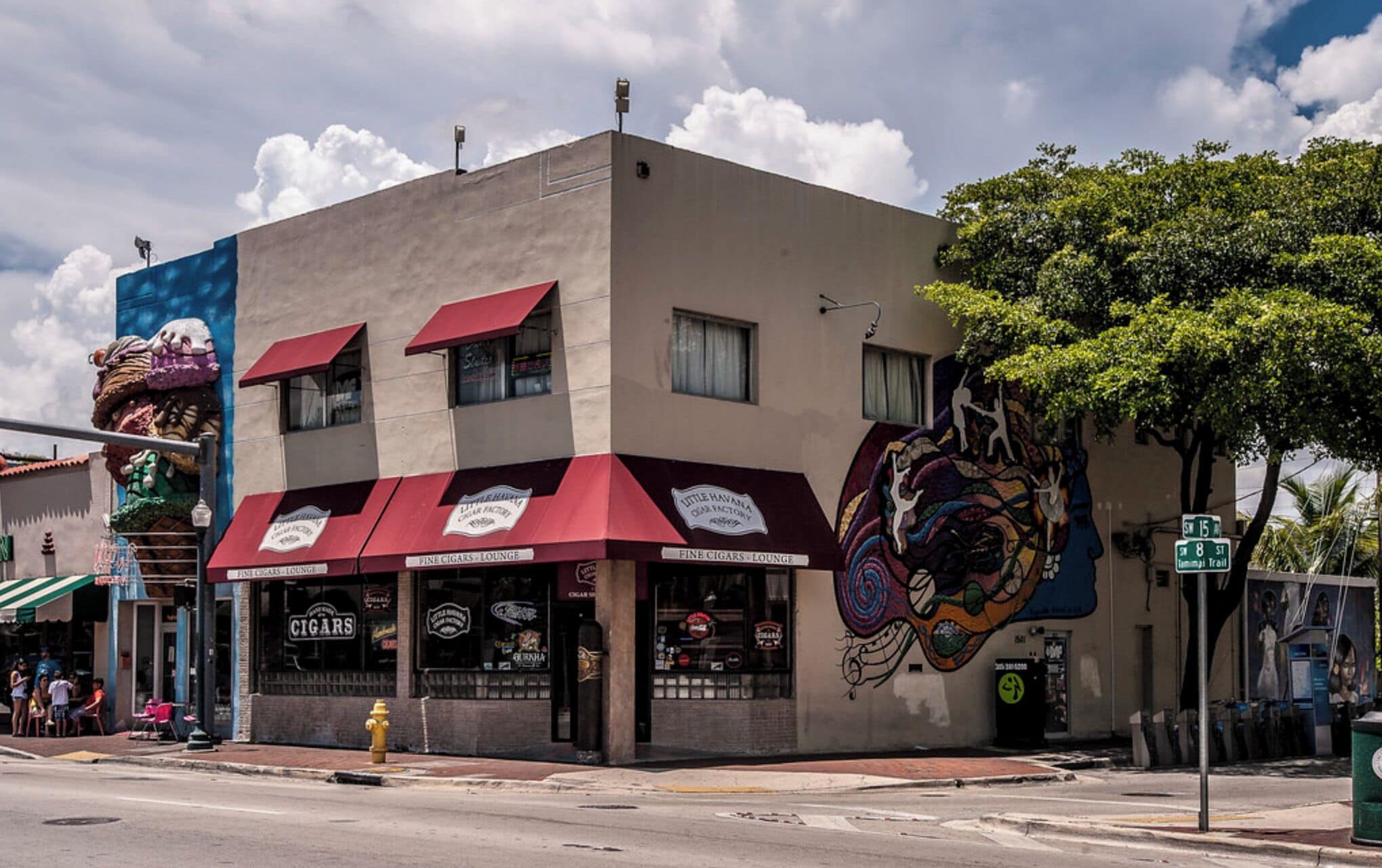 A building with a mural, a red awning, and a sign for 'FINE CIGARS - LOUNGE'.