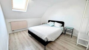 Une chambre à coucher avec un lit, une table de chevet, un radiateur et une fenêtre.