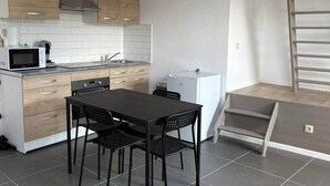 Une cuisine compacte comprenant un coin repas, un four à micro-ondes, un petit réfrigérateur et un escalier menant à un niveau supérieur.