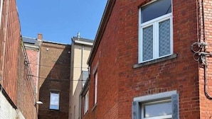 Une ruelle étroite entre deux bâtiments, avec un tuyau rouge qui traîne par terre.