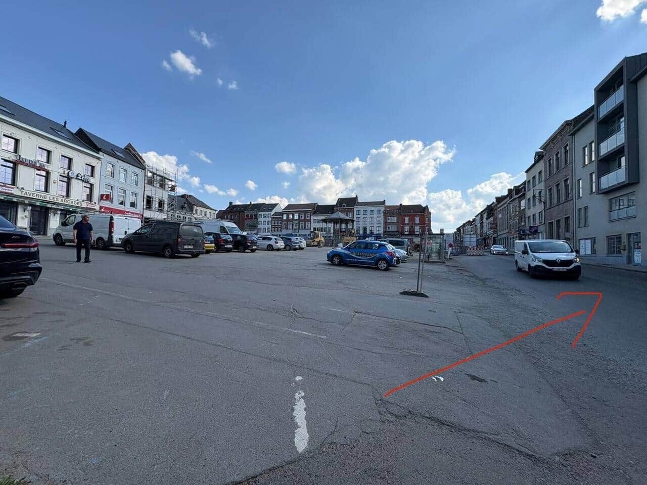 A street with parked cars, buildings, and a clear sky.
