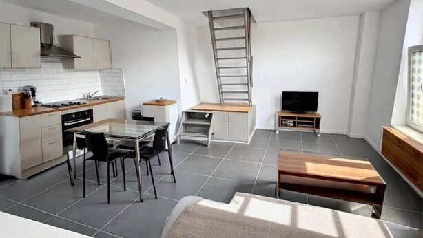 Une cuisine compacte avec un coin repas, un téléviseur et un lit en mezzanine.