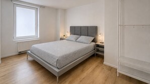 Ein Schlafzimmer mit Bett, Nachttischen, einem Fenster und einem Kleiderschrank.