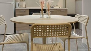 A compact kitchen with a round dining table, two chairs, and a built-in stove.