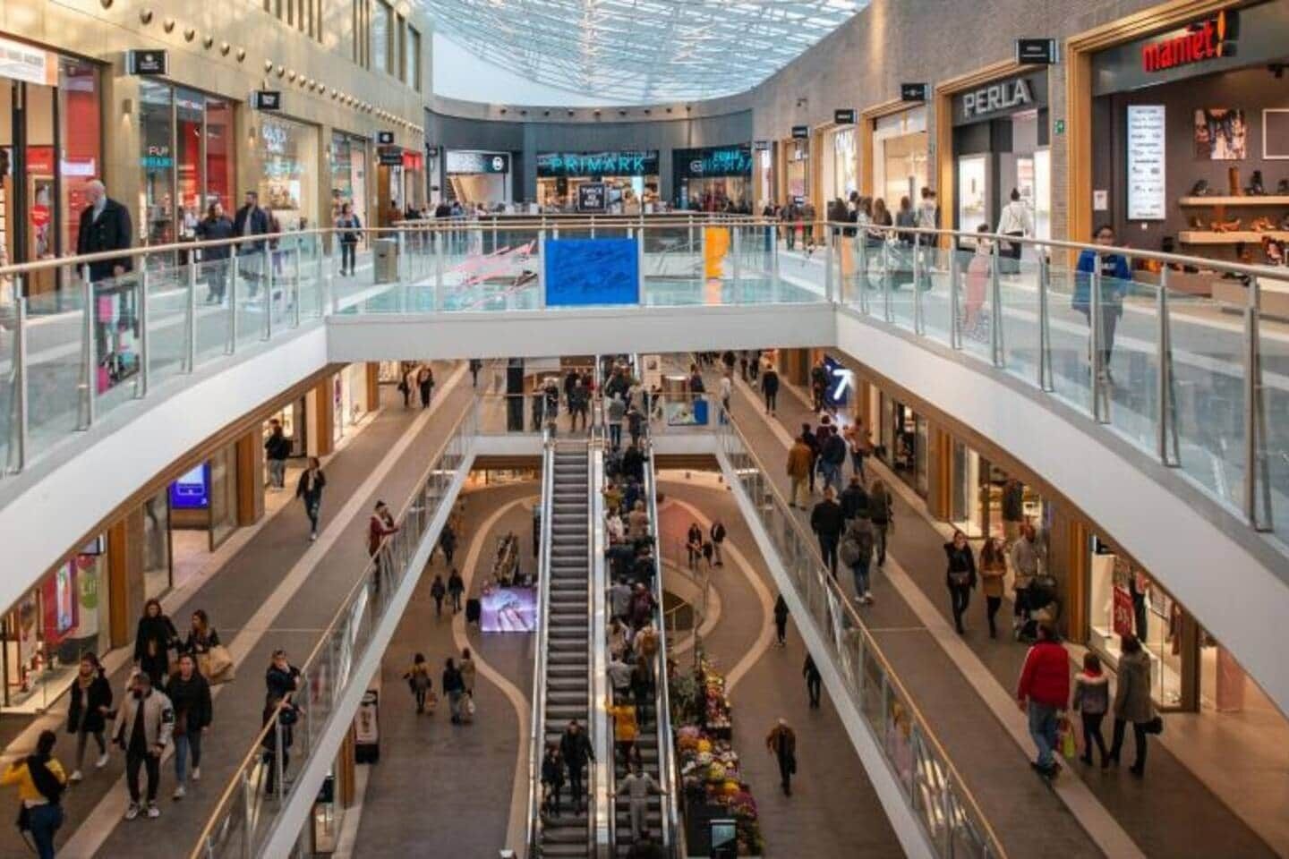 A multi-level shopping mall with various stores, including a visible Primark and a Perla store.