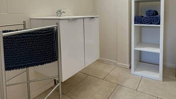 Une salle de bain équipée d’un miroir, d’un lavabo, d’un porte-serviettes et d’un meuble de rangement contenant des serviettes.