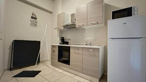Une cuisine compacte équipée d’un réfrigérateur, d’un four à micro-ondes, d’une cuisinière et de placards.