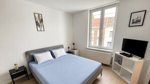 Ein Schlafzimmer mit einem Bett, einem Fernseher, einem Fenster und Bildern an den Wänden.