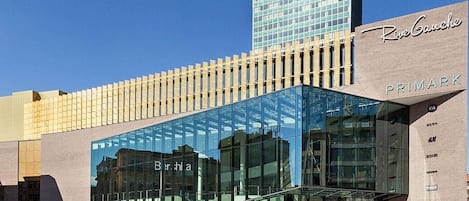 A modern building with a glass facade, a prominent sign for 'Riv Gauche,' and a visible entrance.