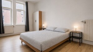 Ein Schlafzimmer mit einem Bett, zwei Nachttischen, einem Kleiderschrank und einer Heizung.