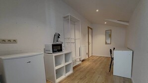 A small, clean room with a white refrigerator, a microwave, a white cabinet, and a chair.