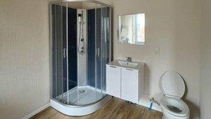 Une salle de bain avec une douche à parois de verre, un lavabo blanc et des toilettes.